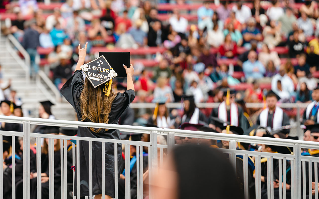 Female student showing her diploma to the crowd at commencement ceremony. 