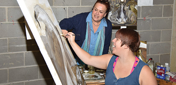 Instructor watching a student paint.