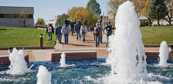 Students walking behind the fountain in University Plaza