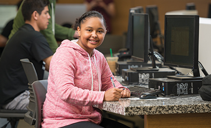 Young student in the Library building smiling at the camera