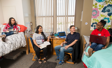 four students hanging out in a typical dorm room