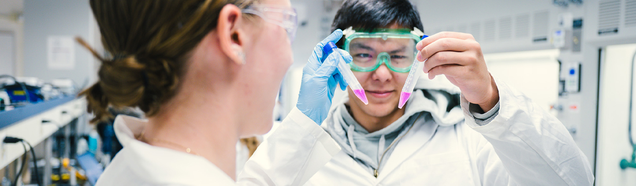 Students in lab coats looking at computer