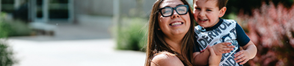 Older CSU student smiling with her son and posing to the camera.