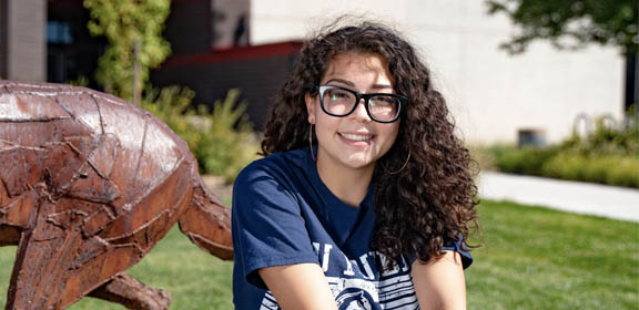 CSU Pueblo high school student sitting on campus smiling at camera