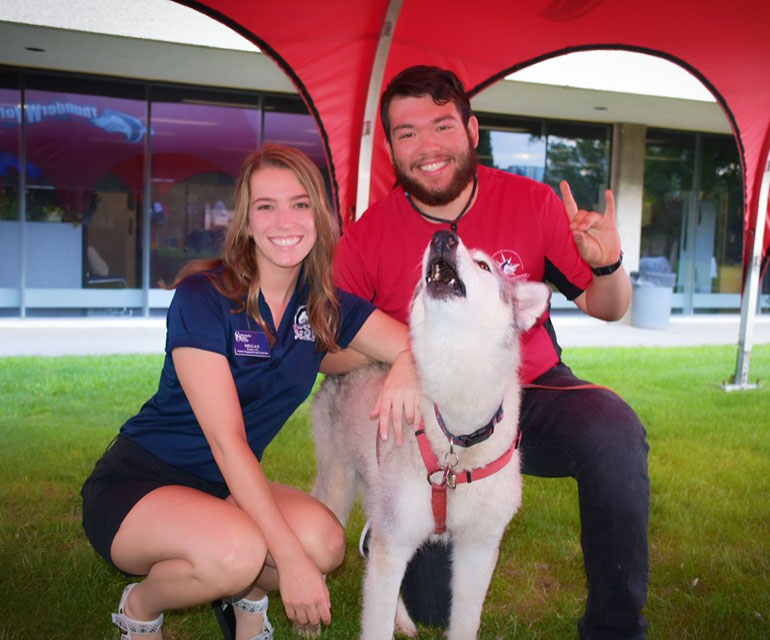 Students smiling at the camera with mascot, Tundra