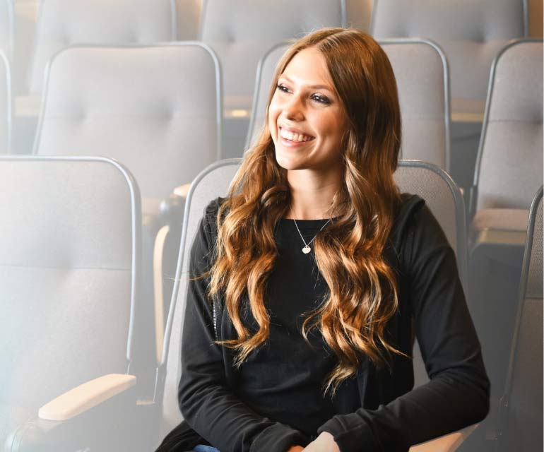 CSU Pueblo student sits in classroom auditorium smiling off to the side