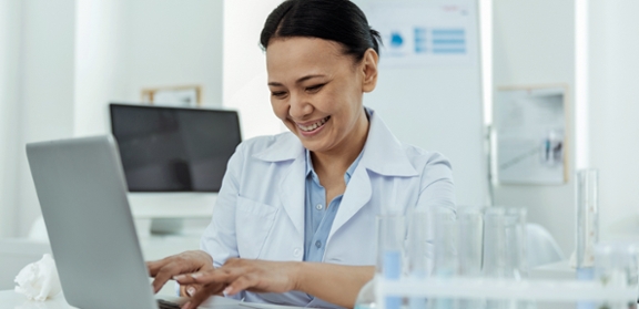 nurse on computer in lab smiling