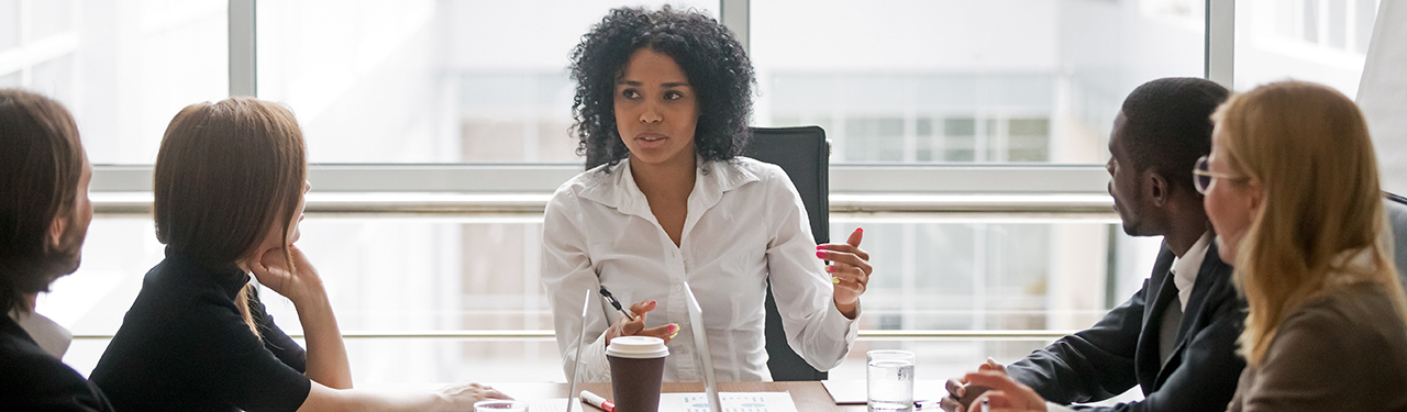 Woman running a meeting with other individuals at a table