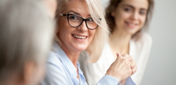 A woman smiling in front of a table of students.