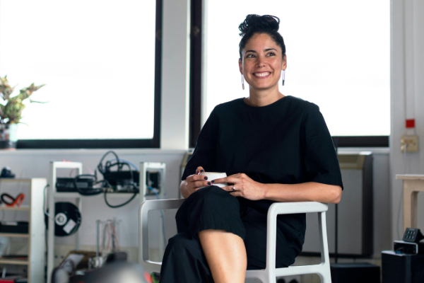 Woman sitting in a chair, smiling, drinking a cup of coffee