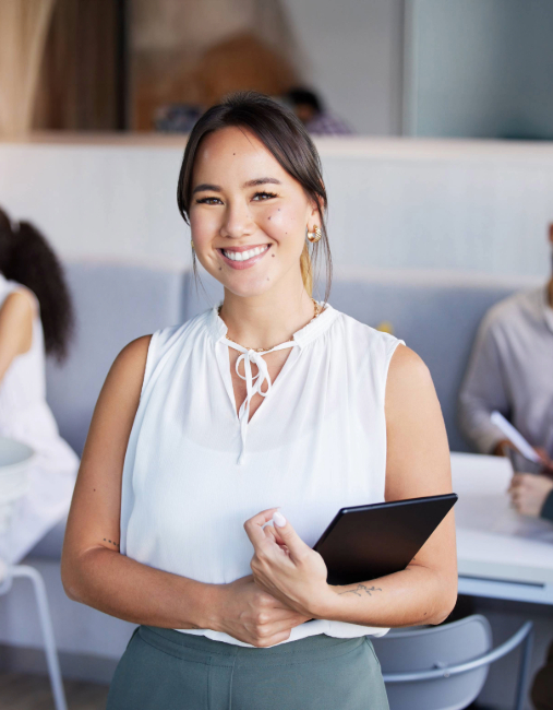 Woman smiling with a clipboard in hand in a room.