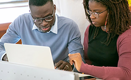 two individuals looking at laptop