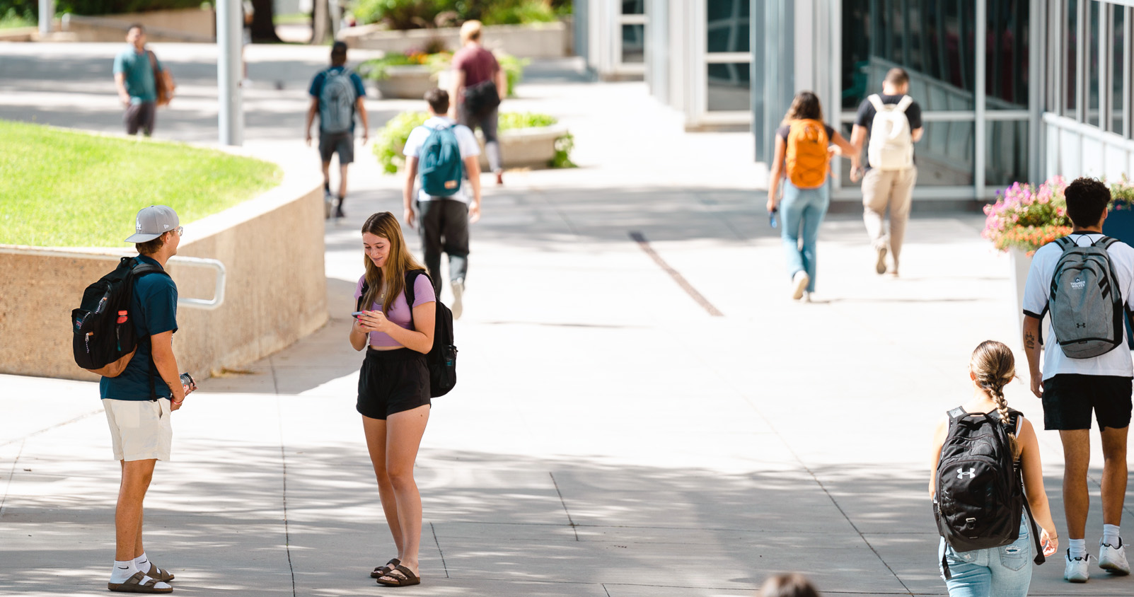STUDENTS WALKING IN FRONT OF THE LIBRARY ON SUMMER DAY